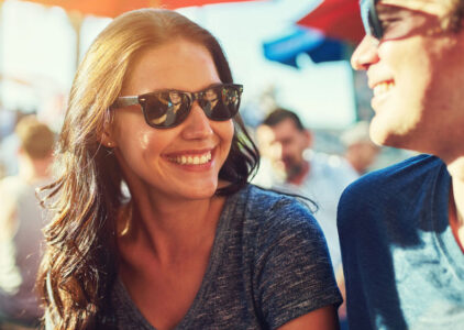Frau und Mann mit Sonnenbrille lächeln sich an