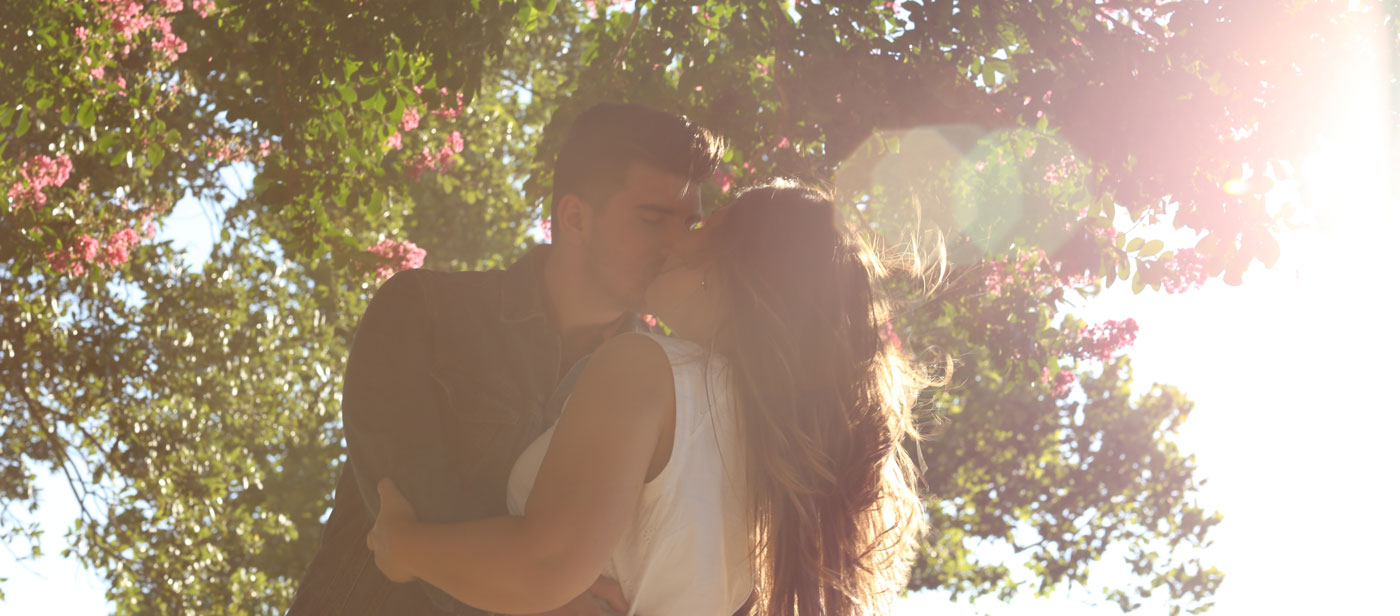 Frau und Mann küssen sich unter blühendem Baum